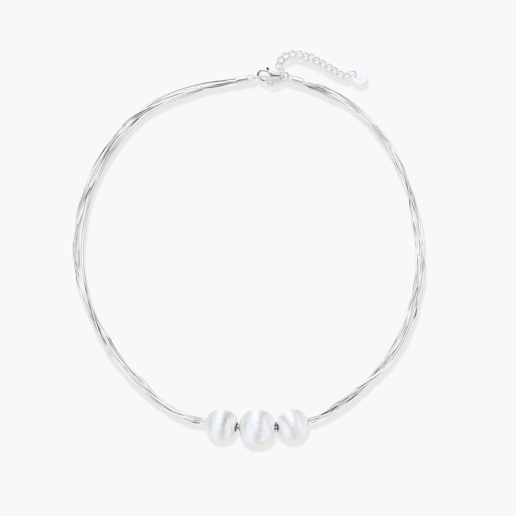 Sterling silver multi-strand necklace with three brushed round beads on cream background