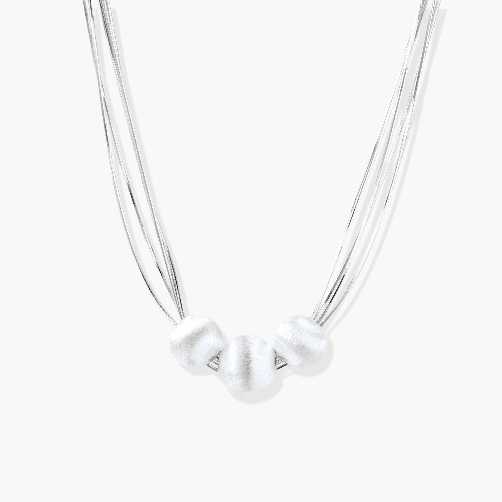 Sterling silver multi-strand necklace with three brushed round beads on cream background